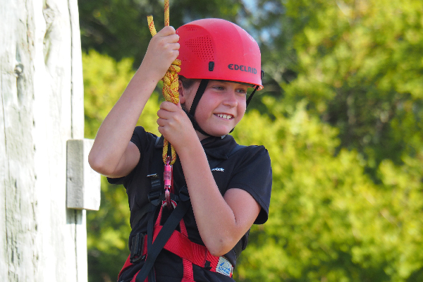 young girl smiling while hanging on a rope from the tower