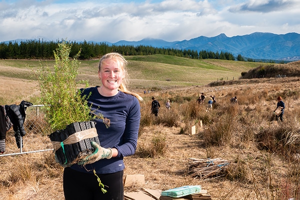 student holding native tree for planting